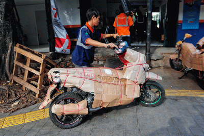 Pekerja tengah mengepak sepeda motor yang akan di kirim melalui jasa pengiriman dengan kereta api di Kawasan Stasiun Senen, Jakarta, Senin (17/4/2023).