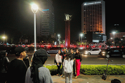 Sejumlah warga berswafoto di kawasan Bundaran HI, Jakarta, Minggu (23/4/2023).