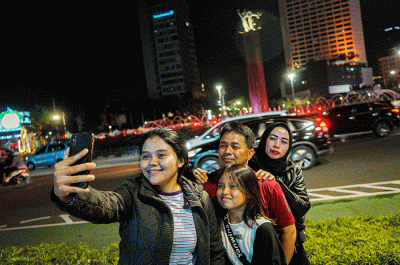 Sejumlah warga berswafoto di kawasan Bundaran HI, Jakarta, Minggu (23/4/2023).