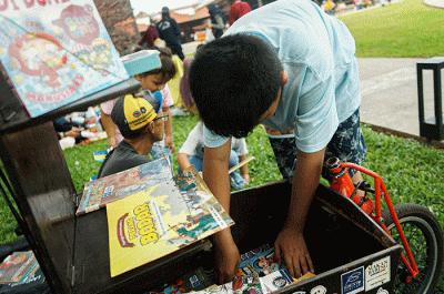 Seorang anak membaca buku gratis yang digelar oleh Kargo Baca di Taman Mini Indonesia Indah (TMII), Jakarta, Minggu (23/4/2023).