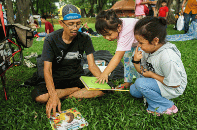 Seorang anak membaca buku gratis yang digelar oleh Kargo Baca di Taman Mini Indonesia Indah (TMII), Jakarta, Minggu (23/4/2023).