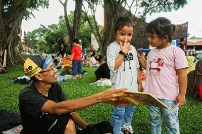 Seorang anak membaca buku gratis yang digelar oleh Kargo Baca di Taman Mini Indonesia Indah (TMII), Jakarta, Minggu (23/4/2023).