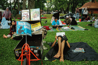 Seorang anak membaca buku gratis yang digelar oleh Kargo Baca di Taman Mini Indonesia Indah (TMII), Jakarta, Minggu (23/4/2023).