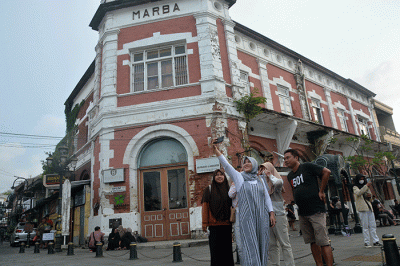 Sejumlah wisatawan berswafoto dengan latar belakang bangunan kuno dan bersejarah di kawasan Kota Lama Semarang, Jawa Tengah, Selasa (25/4/2023).