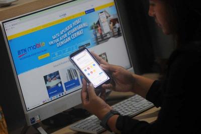 Seorang nasabah bertransaksi menggunakan aplikasi BTN Mobile di Jakarta, Jumat (5/5/2023).