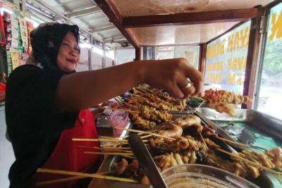 Pedagang makanan melayani pembeli di kawasan Persada Kuningan Raya, Jakarta, Sabtu (27/5/2023).