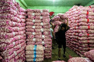 Pekerja memindahkan stok bawang putih dari gudang ke atas mobil di Pasar Induk Kramat Jati, Jakarta, Selasa (30/5/2023).