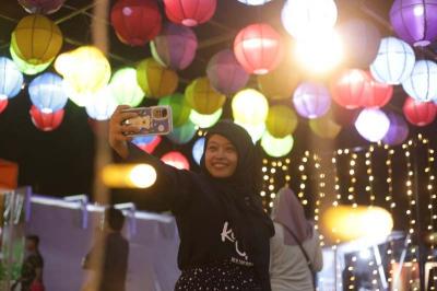 Warga berswafoto di area Makassar Light Festival Lapangan Hasanuddin, Makassar.