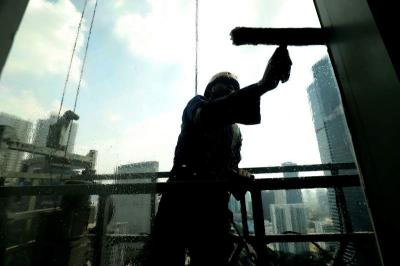 Pekerja menggunakan perlengkapan keamanan lengkap melakukan perawatan gedung bertingkat di Jakarta, Jumat (23/6/2023).