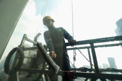 Pekerja menggunakan perlengkapan keamanan lengkap melakukan perawatan gedung bertingkat di Jakarta, Jumat (23/6/2023).