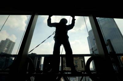 Pekerja menggunakan perlengkapan keamanan lengkap melakukan perawatan gedung bertingkat di Jakarta, Jumat (23/6/2023).