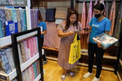 Pengunjung melakukan scan QR saat berbelanja diskon hingga 70% dan ekstra diskon hingga Rp5 juta di booth Blibli Hall B3, PRJ 2023.