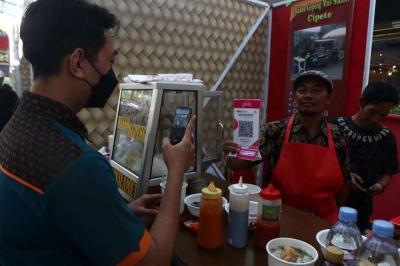 Pembeli melakukan pembayaran secara digital menggunakan QRIS pada salah satu warung di Jakarta, Minggu (30/7/2023).