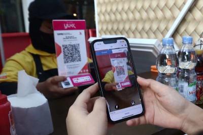 Pembeli melakukan pembayaran secara digital menggunakan QRIS pada salah satu warung di Jakarta, Minggu (30/7/2023).