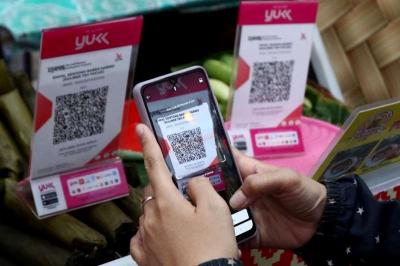 Pembeli melakukan pembayaran secara digital menggunakan QRIS pada salah satu warung di Jakarta, Minggu (30/7/2023).