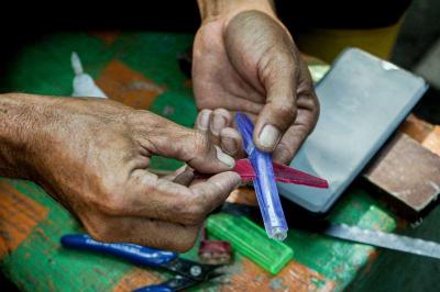 Timan memanfaatkan limbah korek api gas untuk dijadikan kerajinan tangan miniatur di Pos UPS Badan Air Kali Utan Kayu