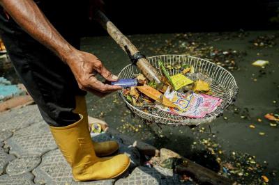 Timan mengumpulkan limbah korek api gas dari sampah Kali Utan Kayu