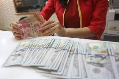 Karyawati menunjukkan mata uang rupiah dan dolar Amerika Serikat di tempat penukaran uang asing Agung Masayu di Jakarta, Selasa (24/10/2023).