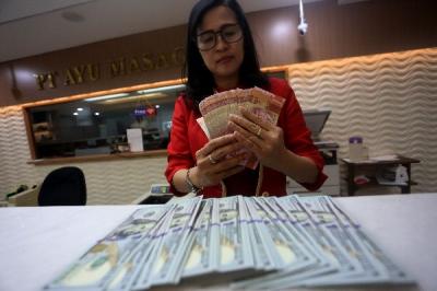 Karyawati menunjukkan mata uang rupiah dan dolar Amerika Serikat di tempat penukaran uang asing Agung Masayu di Jakarta, Selasa (24/10/2023).