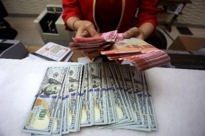 Karyawati menunjukkan mata uang rupiah dan dolar Amerika Serikat di tempat penukaran uang asing Agung Masayu di Jakarta, Selasa (24/10/2023).