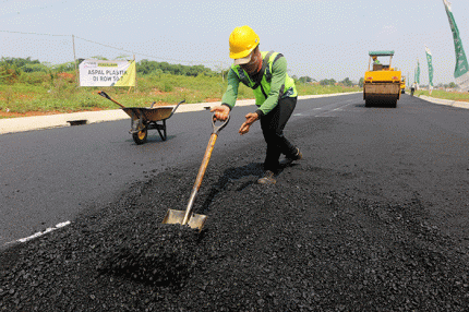 Pekerja menyelesaikan proyek pengaspalan plastik di kawasan BSD City, Tangerang, Banten, Kamis (21/7/2022).