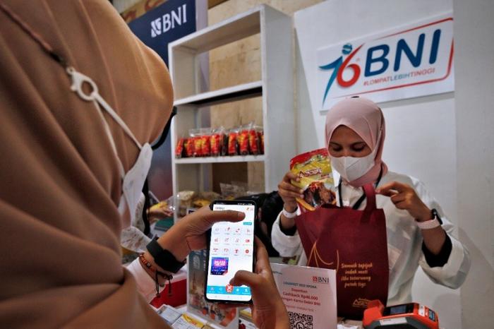 Pengunjung BNI Loud Fest tengah berbelanja menggunakan BNI Mobile Banking di Jakarta Convention Center, Minggu (17/7/2022).