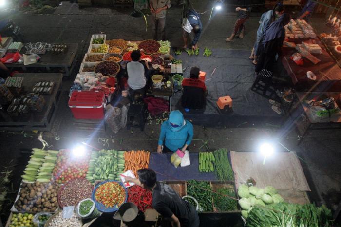 Pedagang dan pembeli beraktivitas di Pasar Kramat Jati, Jakarta Timur, Sabtu (27/2/2021) malam.