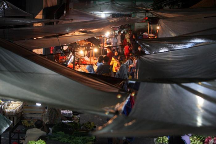 Pedagang dan pembeli beraktivitas di Pasar Kramat Jati, Jakarta Timur, Sabtu (27/2/2021) malam.