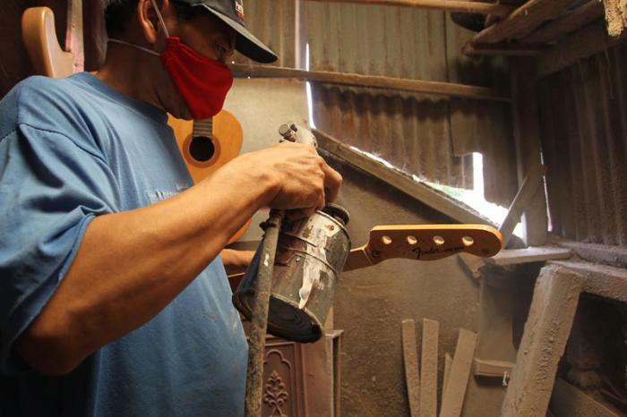 Pekerja menyelesaikan pembuatan gitar di sentra produksi dan reparasi gitar Pak Manto, Jalan Langgar II, Pejaten Timur, Pasar Minggu, Jakarta Selatan, Minggu (7