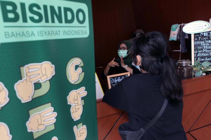 Barista yang merupakan penyandang disabilitas menyajikan minuman kopi pesanan pelanggan di Difabis Coffee & Tea