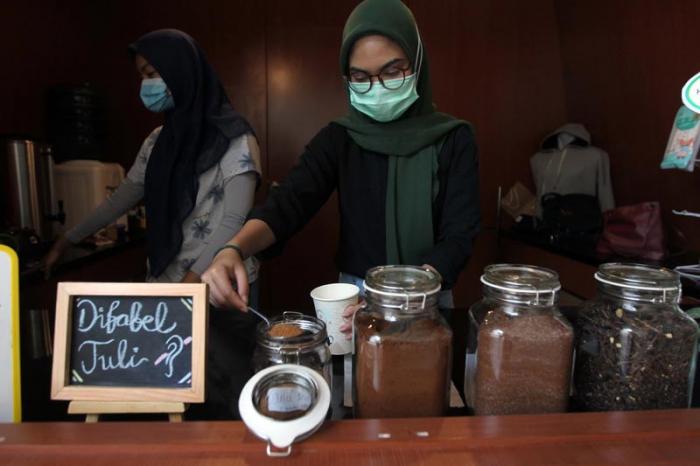 Barista yang merupakan penyandang disabilitas menyajikan minuman kopi pesanan pelanggan di Difabis Coffee & Tea