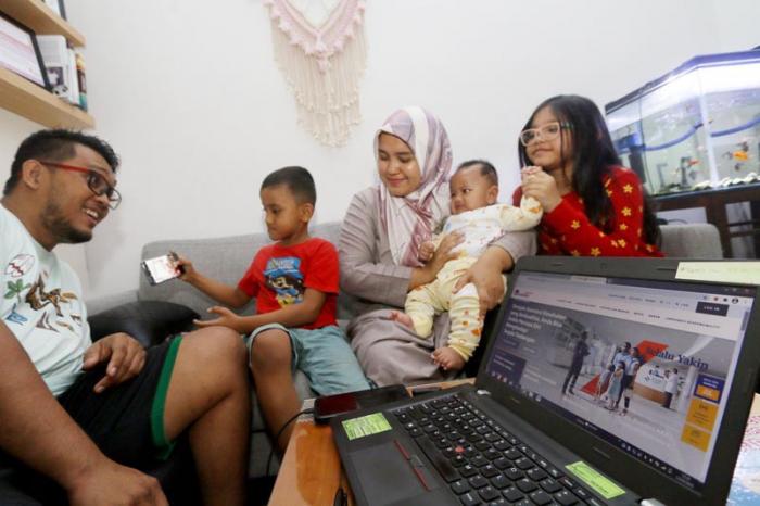 Keluarga bercengkrama sambil mencari informasi asuransi kesehatan melalui website AXA Mandiri di rumahnya di Depok, Jawa Barat