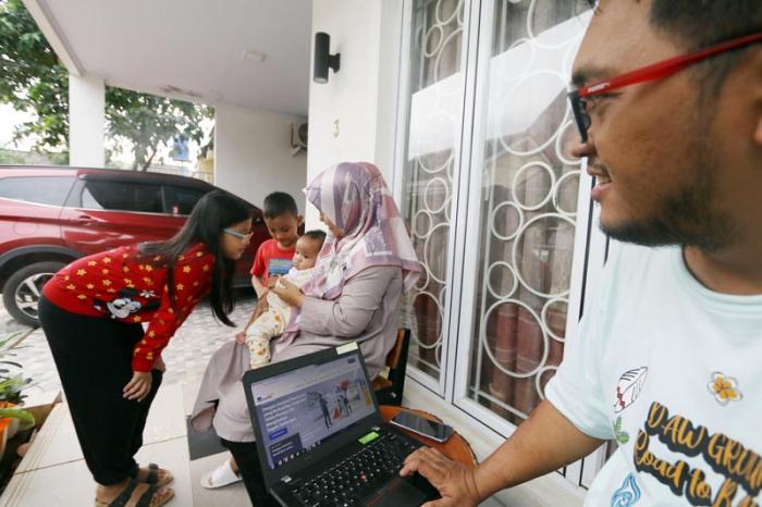 Keluarga bercengkrama sambil mencari informasi asuransi kesehatan melalui website AXA Mandiri di rumahnya di Depok, Jawa Barat