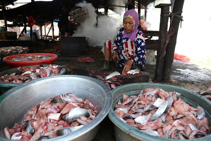 Perajin membersihkan ikan jenis patin di kawasan pesisir Kenjeran Surabaya, Jawa Timur, Kamis (18/3/2021).