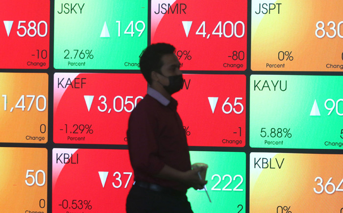 Pengunjung melintasi layar bursa saham di Bursa Efek Indonesia (BEI), Jakarta, Senin (22/3/2021).