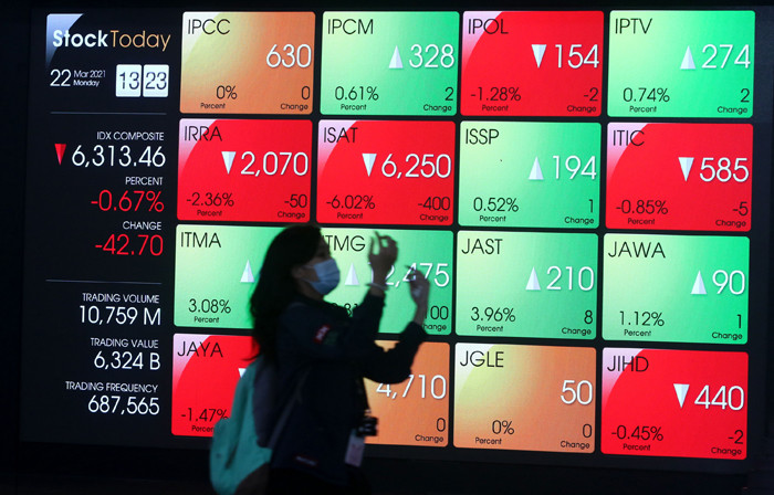 Pengunjung melintasi layar bursa saham di Bursa Efek Indonesia (BEI), Jakarta, Senin (22/3/2021).