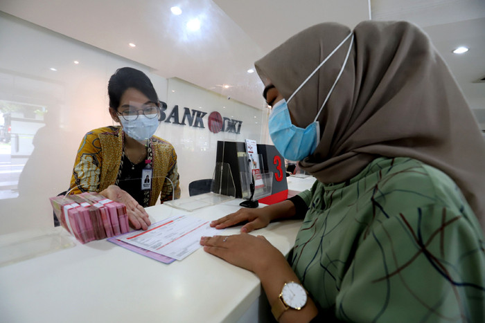 Karyawan menunjukkan uang rupiah di salah satu Kantor Cabang Bank DKI, Jakarta, Jumat (26/3/2021).