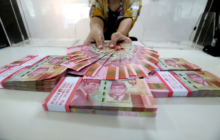 Karyawan menunjukkan uang rupiah di salah satu Kantor Cabang Bank DKI, Jakarta, Jumat (26/3/2021).