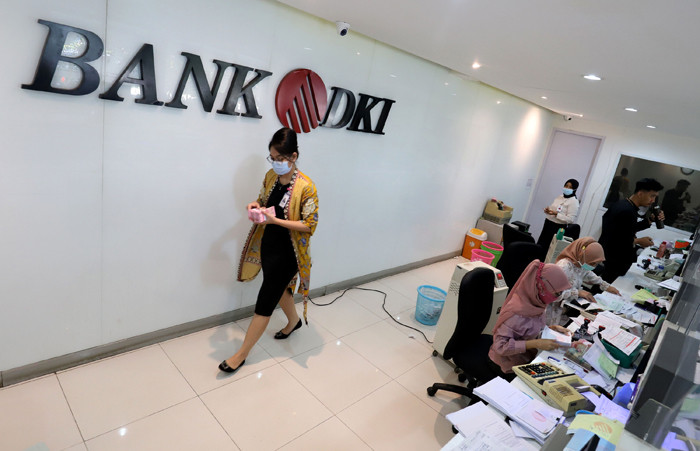 Karyawan menunjukkan uang rupiah di salah satu Kantor Cabang Bank DKI, Jakarta, Jumat (26/3/2021).