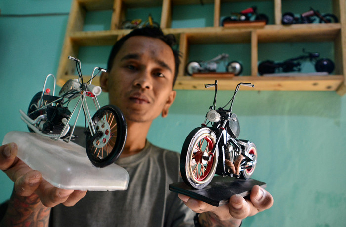 Pengrajin Andriatna Marbela menyelesaikan pesanan miniatur motor custom dari limbah plastik di Kemang, Bogor, Jawa Barat, Sabtu (27/3/2021).