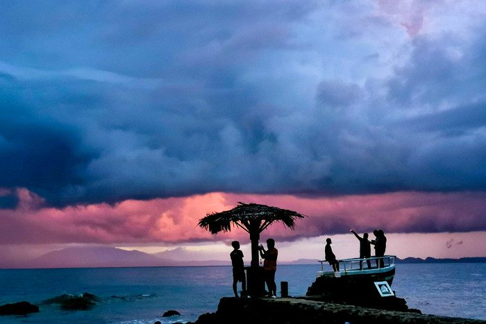 Pengunjung menikmati keindahan panorama matahari terbenam di Pantai Anyer, Serang, Banten, Sabtu (27/3/2021).