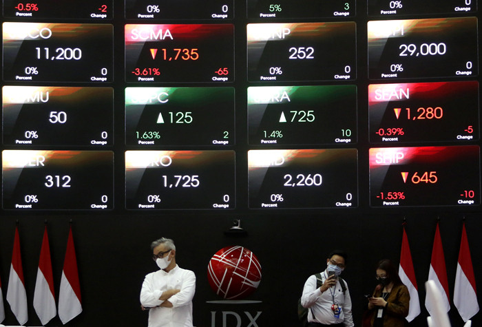 Pengunjung melintasi layar bursa saham di Bursa Efek Indonesia (BEI), Jakarta, Selasa (30/3/2021).