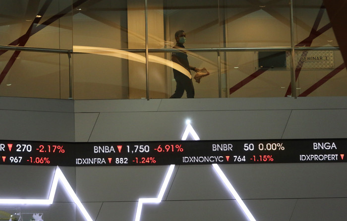Pengunjung melintasi layar bursa saham di Bursa Efek Indonesia (BEI), Jakarta, Selasa (30/3/2021).