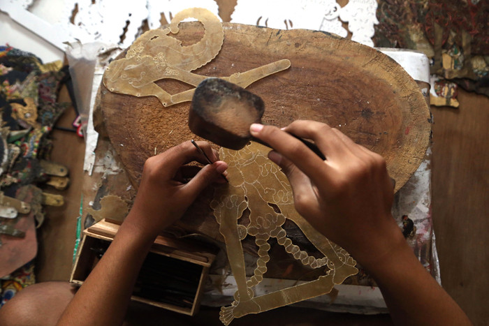 Perajin wayang Ahmad Maiyo Satria Tama (16) menyelesaikan pembuatan dan perbaikan wayang di Surabaya, Jawa Timur, Rabu (31/3/2021).