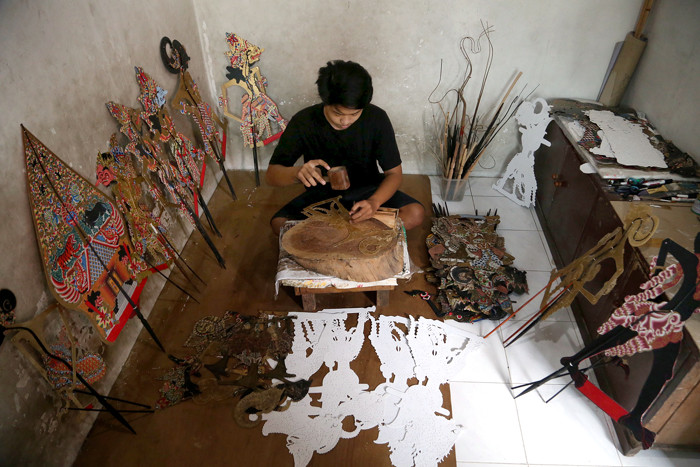 Perajin wayang Ahmad Maiyo Satria Tama (16) menyelesaikan pembuatan dan perbaikan wayang di Surabaya, Jawa Timur, Rabu (31/3/2021).