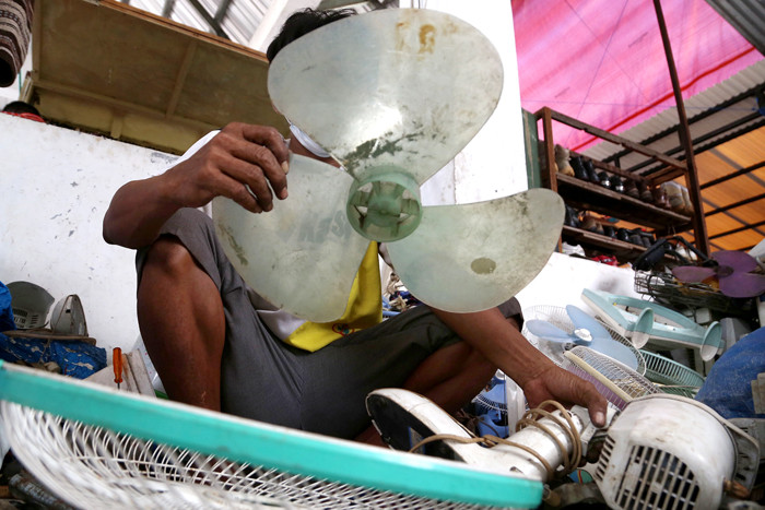 Tukang servis kipas angin, Musyafak menyelesaikan perbaikan kipas angin di Pasar Loak Gembong Surabaya, Jawa Timur, Kamis (1/4/2021).