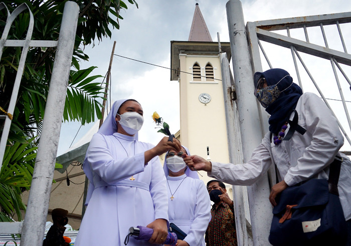 Peserta aksi yang tergabung dalam Forum Rakyat Bersatu memegang bunga saat aksi solidaritas di depan Gereja Katedral, Makassar, Sulsel, Minggu (4/4/2021).