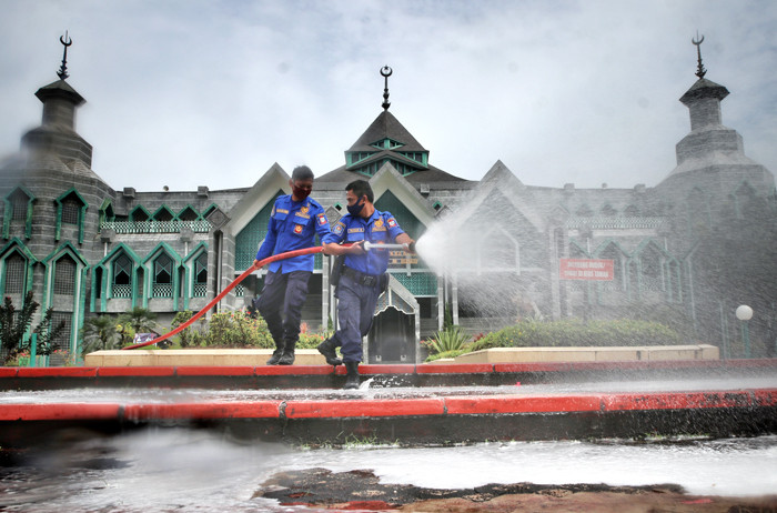 Petugas pemadam kebakaran tengah menyemprotkan cairan disinfektan di Masjid Al Markaz Al Islami, Makassar, Sulawesi Selatan, Kamis (8/4/2021).