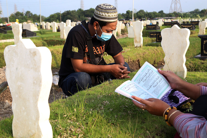Peziarah berdoa dipisara makam kerabatnya yang dimakamkan di makam khusus Covid-19, Keputih Surabaya, Jawa Timur, Jumat (9/4/2021).