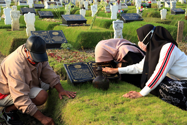 Peziarah berdoa dipisara makam kerabatnya yang dimakamkan di makam khusus Covid-19, Keputih Surabaya, Jawa Timur, Jumat (9/4/2021).